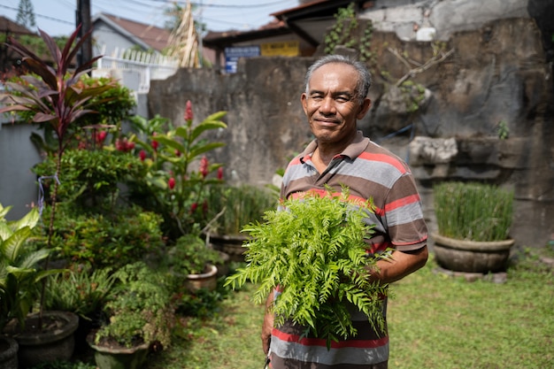 Homem asiático sênior com algumas plantas na mão