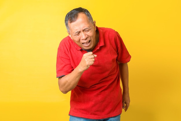 Homem asiático sênior tossindo isolado em fundo amarelo