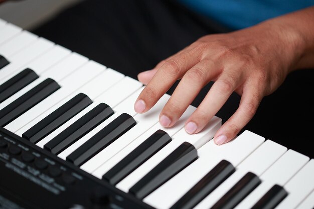 Homem asiático sentado em casa a praticar piano