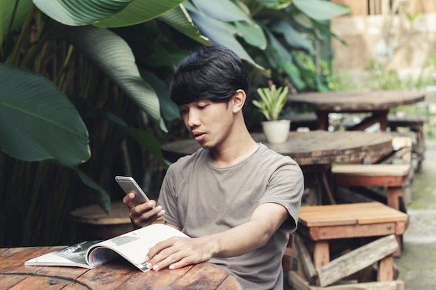 Homem asiático sentado em um café ocupado com o telefone