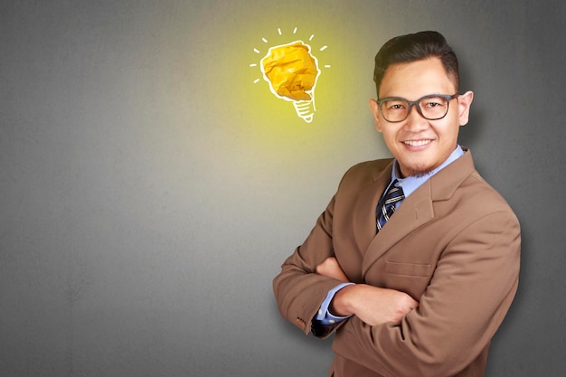 Homem asiático sorrindo feliz com lâmpada de lâmpada brilhante feita de papel símbolo de ideia e inovação