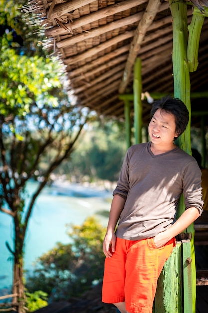 Homem asiático tailandês chinês sorri e relaxa neste dia de férias no fim de semana no ambiente natural em um pavilhão vintage verde