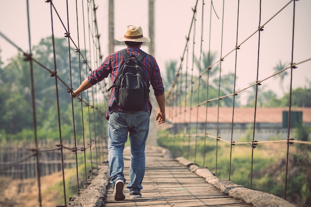 Homem asiático turista andando na ponte de madeira velha e quebrada