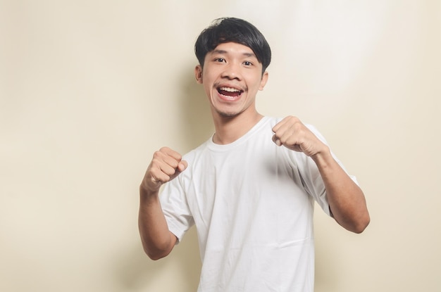 Homem asiático vestindo camiseta branca com gesto feliz em fundo isolado