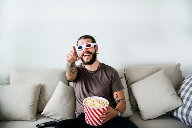 Homem assistindo filme segurando um balde de pipoca