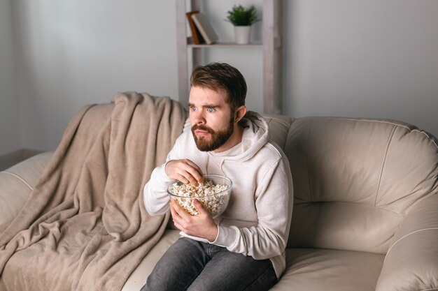 Homem assistindo filmes sentado em um sofá em casa