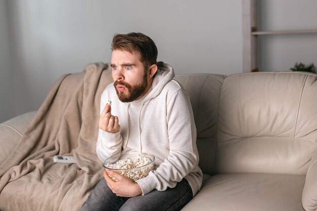 Homem assistindo filmes sentado em um sofá em casa