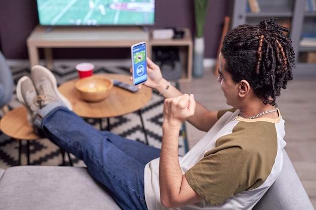 Homem assistindo jogo de futebol em casa e ganhando aposta online