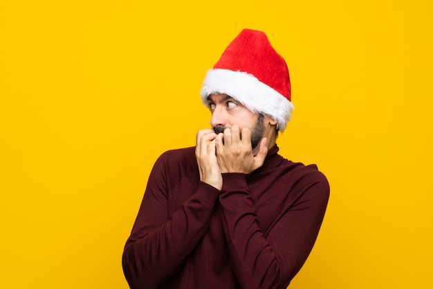 Homem assustado com chapéu de natal sobre fundo amarelo isolado