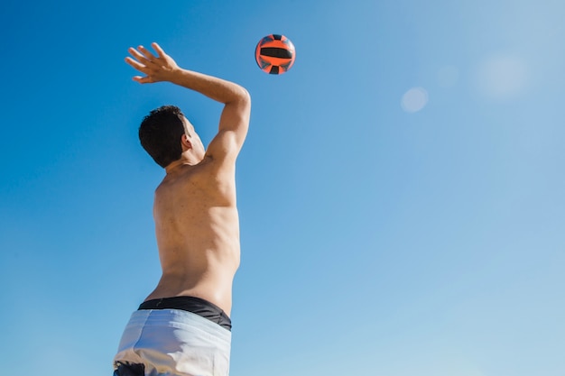 Foto homem atingindo voleibol em um dia ensolarado