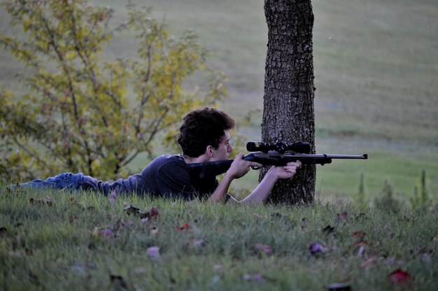 Foto homem atirando com arma no campo