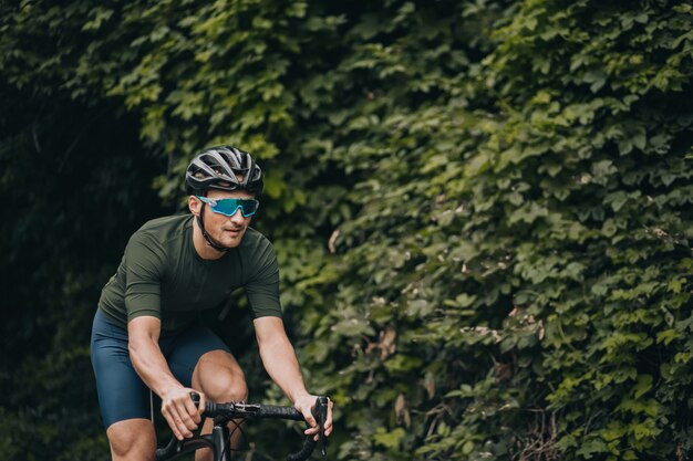 Homem ativo em roupas esportivas, aproveitando o ciclismo matinal no parque