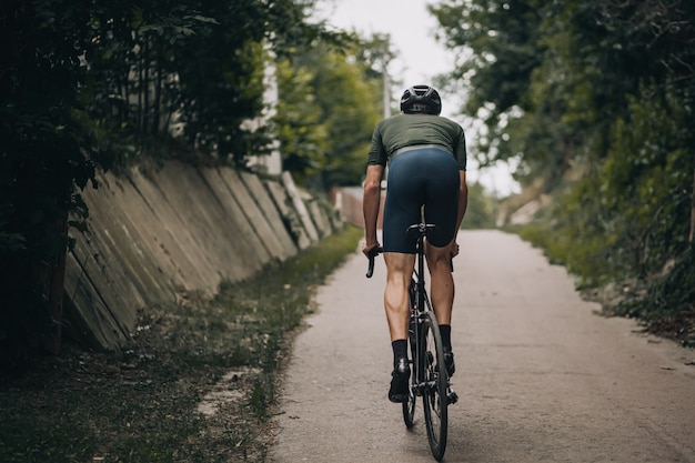 Homem ativo em roupas esportivas e capacete andando de bicicleta ao ar livre