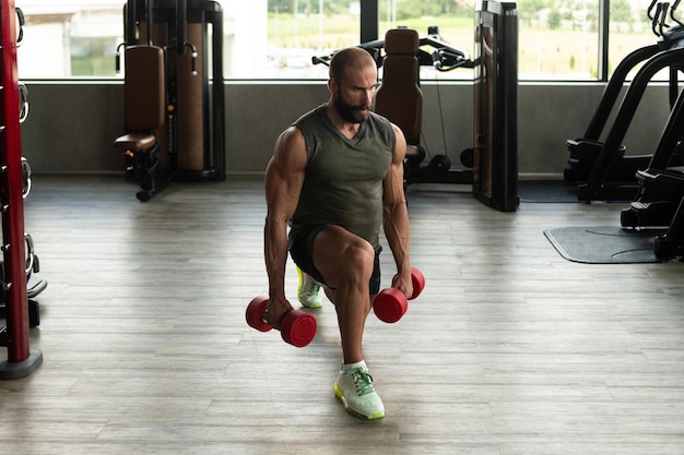 Homem atleta exercitando glúteos com haltere