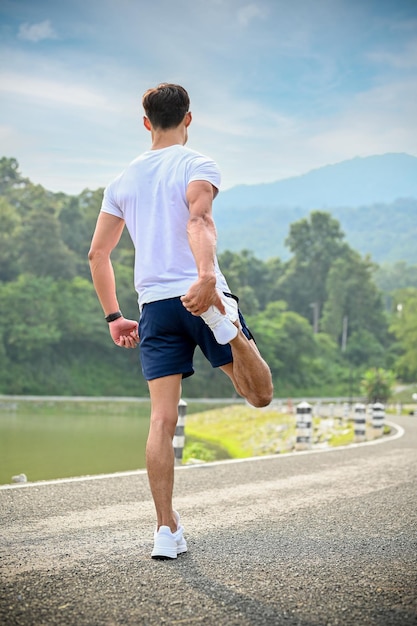 Homem atlético asiático em forma e ativo esticando o aquecimento da perna antes de correr