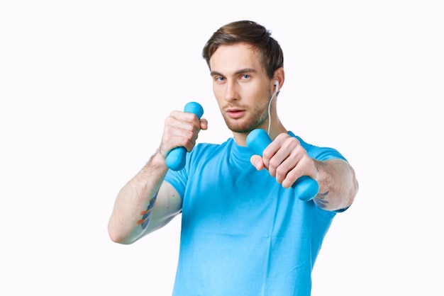 homem atlético com halteres nas mãos camiseta azul cortada vista fitness foto de alta qualidade