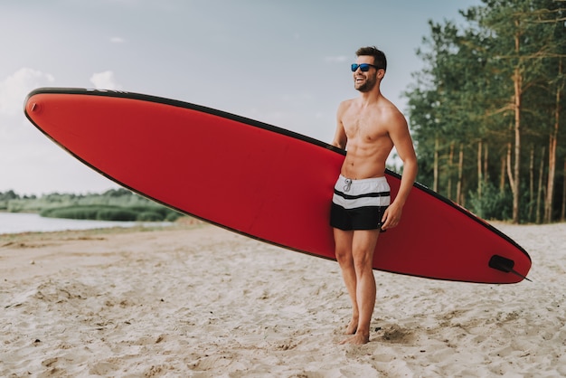 Homem atlético com Surf em pé na praia em Glasess