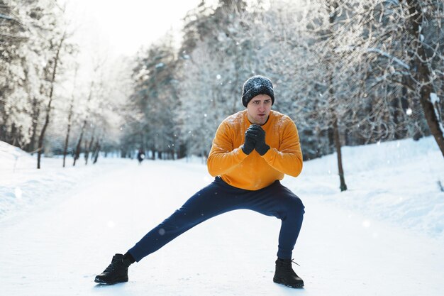 Homem atlético fazendo aquecimento antes de seu treino de inverno de calistenia no parque nevado