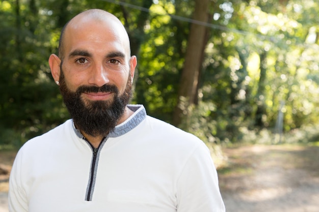 Homem atraente com barba e cabeça careca aproveita o dia de férias ao ar livre