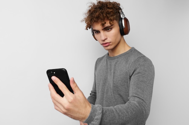 Homem atraente com um telefone na mão ouvindo música em fones de ouvido luz de fundo