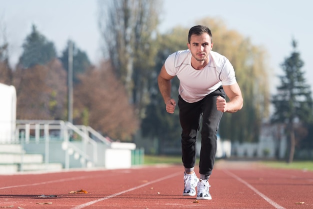 Homem atraente correndo na pista de corrida na área do parque da cidade treinando e exercitando para resistência fitness conceito de estilo de vida saudável ao ar livre