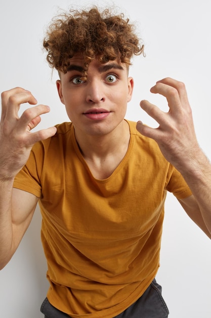 Homem atraente em camiseta amarela gesto mãos emoções luz de fundo