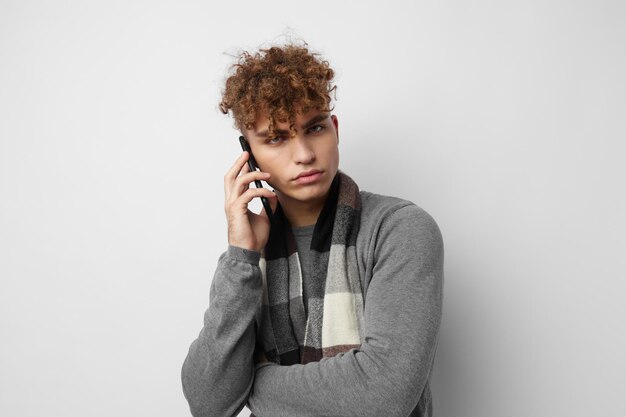 Homem atraente em um cachecol xadrez falando ao telefone posando fundo isolado de emoções