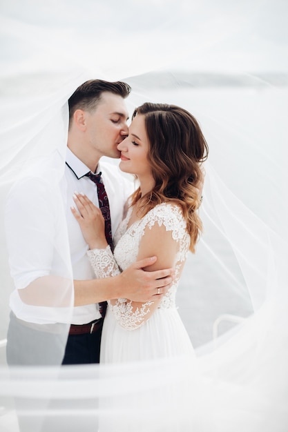 Foto homem atraente em um terno preto e camisa branca com uma linda mulher em um vestido longo branco poses para a câmera em um iate