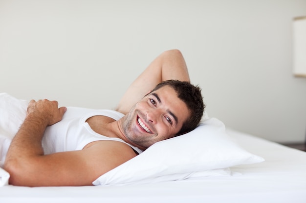 Homem atraente em uma cama sorrindo para a câmera