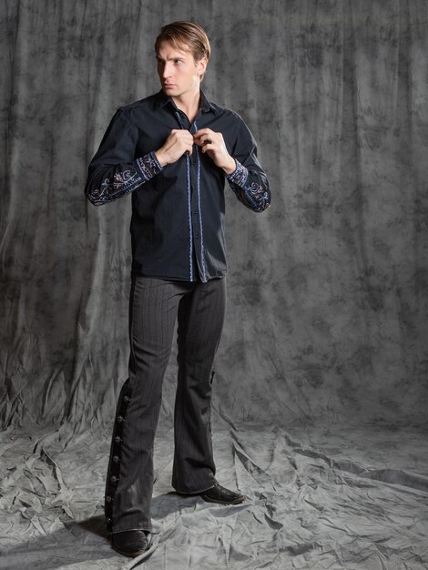 Foto homem atraente em uma camisa elegante com bordado tocando o punho abotoando o botão photo