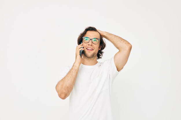 Homem atraente em uma comunicação de camiseta branca por telefone de fundo claro