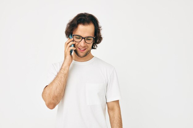 Homem atraente em uma comunicação de camiseta branca por telefone isolado de fundo