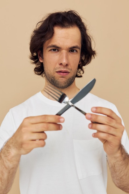 Homem atraente emoções faca e garfo fundo isolado de utensílios de cozinha