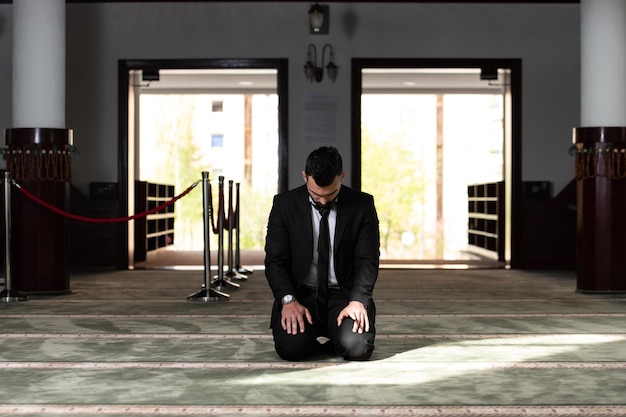 Homem atraente fazendo oração tradicional a Deus Allah na mesquita