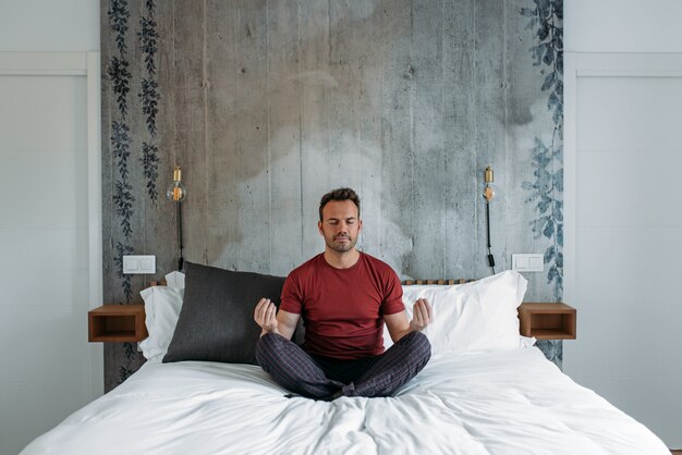 Homem atraente na cama meditando