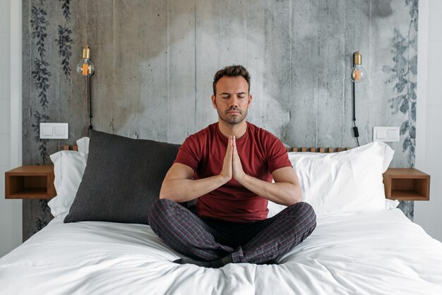 Homem atraente na cama meditando