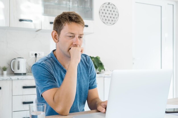 Homem atraente pensativo trabalhando em laptop online em casa usando internet concentrado homem