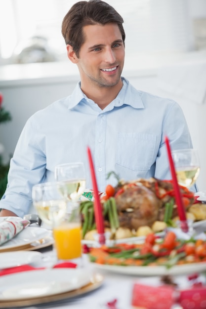 Homem atraente sentado à mesa para o jantar de Natal