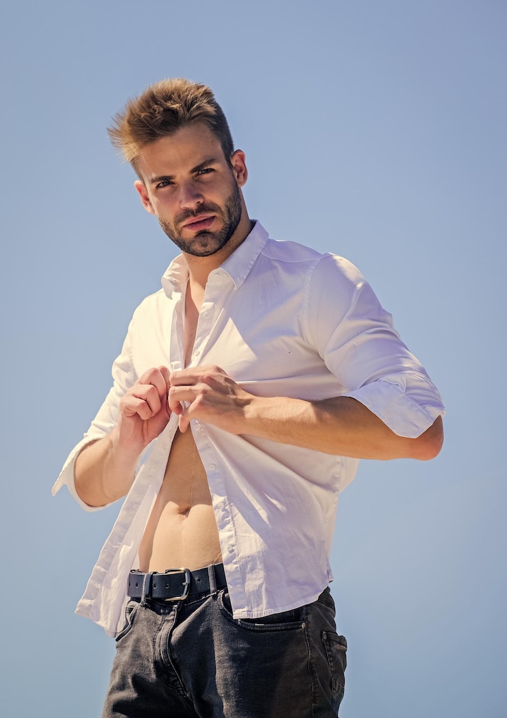 Foto homem atraente tirando a camisa confiante em seu atraente homem barbudo estilo de negócios homem bonito modelo de moda tronco musculoso homem macho musculoso sexy tronco atraente dia quente ao ar livre