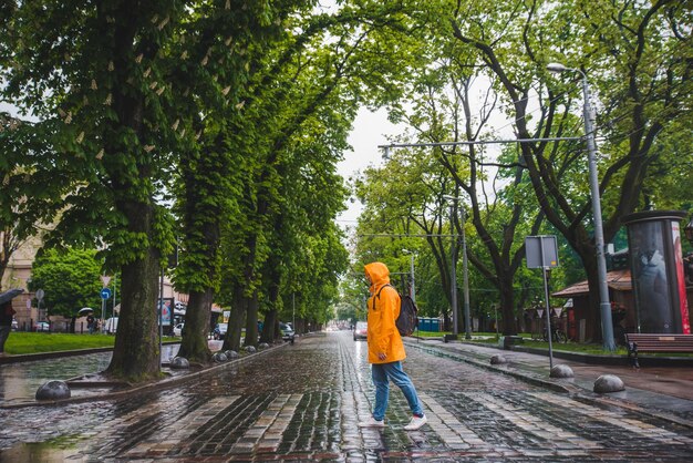 Homem atravessando a rua em tempo nublado de capa de chuva amarela