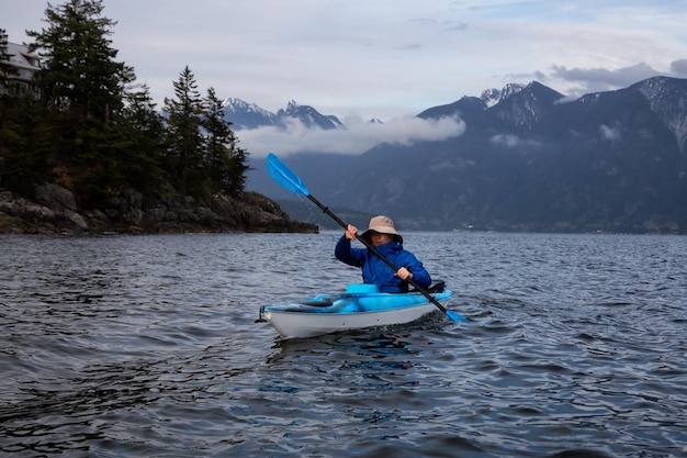 Homem aventureiro em um caiaque está remando em Howe Sound