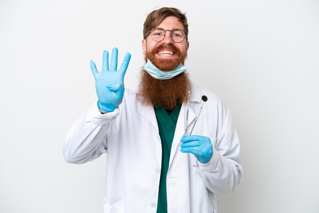 Homem avermelhado dentista segurando ferramentas isoladas em fundo branco feliz e contando quatro com os dedos