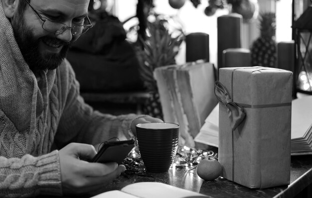 Homem barba escrevendo presentes de Natal em uma mesa com livros antigos