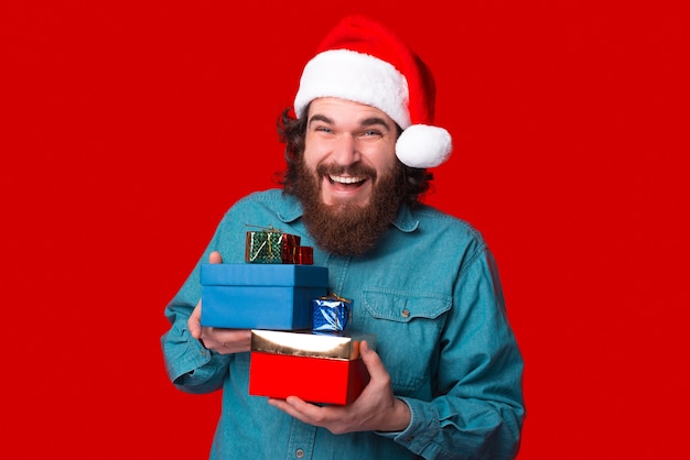 Homem barbudo alegre está segurando algumas caixas de presente para o Natal.