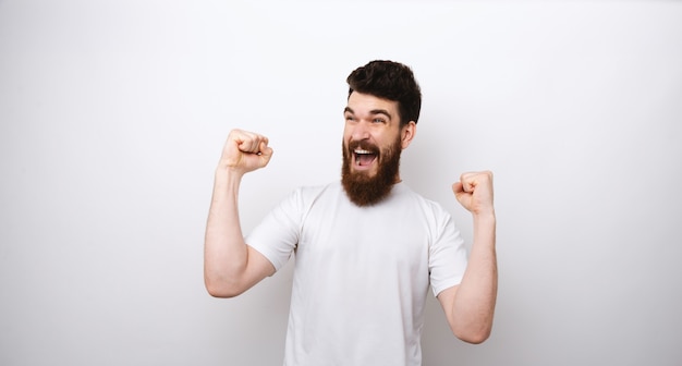 Homem barbudo animado, gritando e comemorando o sucesso com os punhos, conceito de esporte objetivo