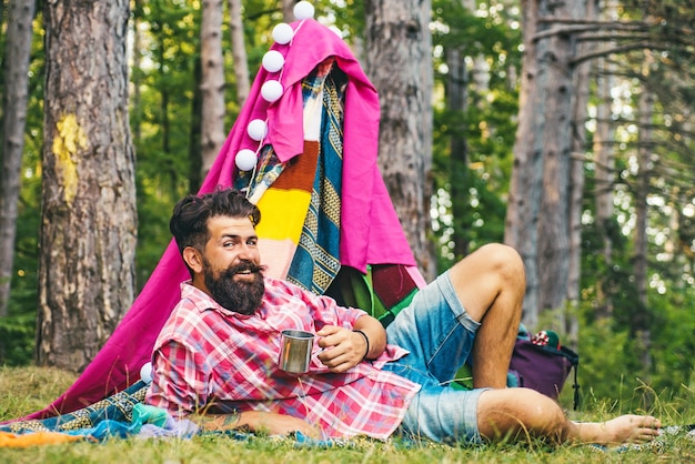 Homem barbudo bonito ao lado da barraca de acampamento