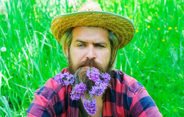 Homem barbudo bonito com flores na barba. Homem com barba decorada.