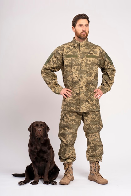 Homem barbudo bonito soldado treinando cão Labrador castanho olhando para longe isolado em fundo branco