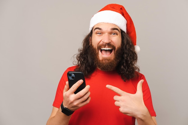 Homem barbudo brincalhão usando pontos de Natal no telefone que está segurando