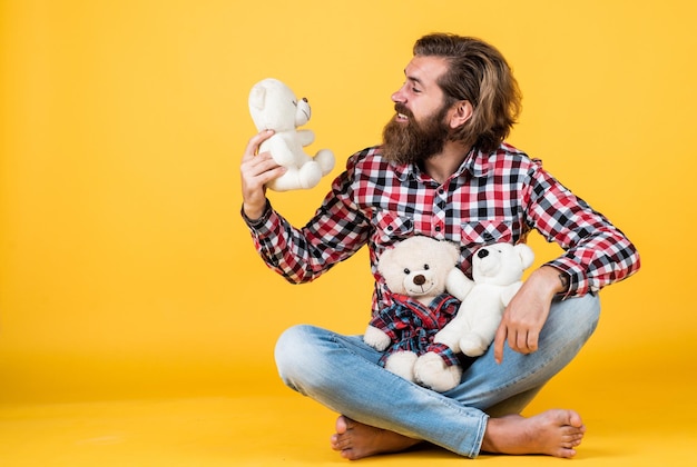 Homem barbudo brutal usa camisa quadriculada com barba e bigode exuberantes com loja de brinquedos de ursinho de pelúcia